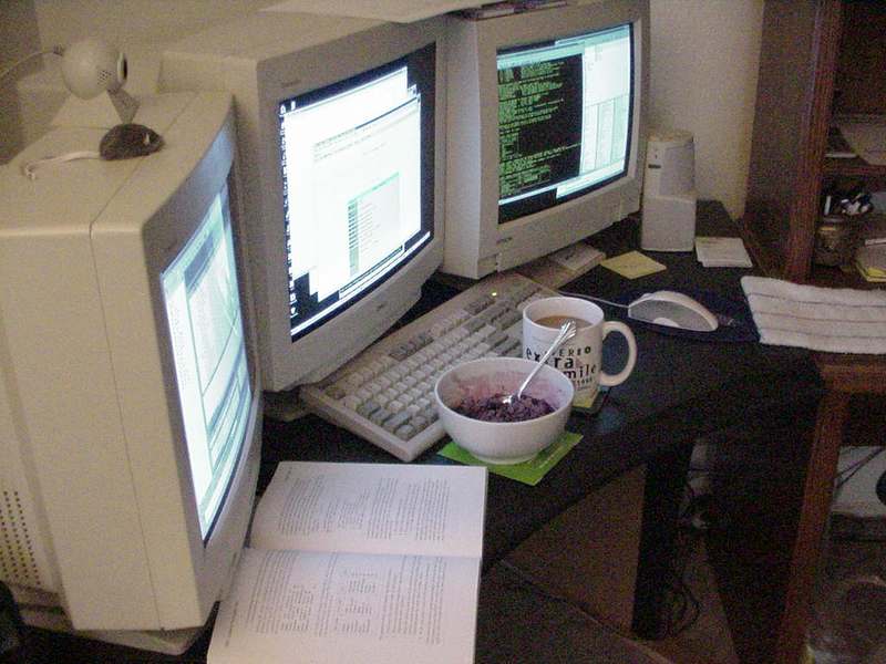 Photo of a desk with 3 computer screens
